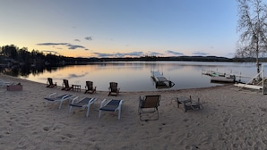 Une plage au bord d’un lac, avec des chaises longues et un quai.