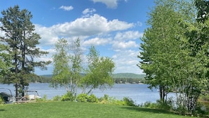 Une zone herbeuse avec des arbres et un lac en arrière-plan.