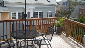 A wooden deck with a red umbrella, metal chairs, and a potted plant. - Beautiful Historic Home Centrally Located  (Provincetown)