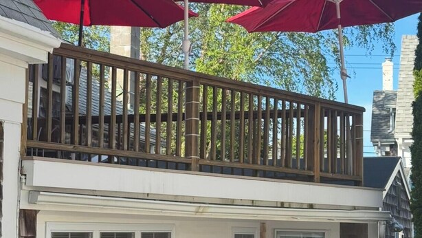 A two-story house with a balcony, a covered porch, and a window with shutters. - Beautiful Historic Home Centrally Located  (Provincetown)