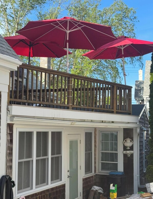 A two-story house with a balcony, a covered porch, and a window with shutters.