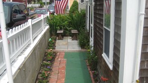 A narrow residential street with a green lawn, a white picket fence, and an American flag. - Beautiful Historic Home Centrally Located  (Provincetown)