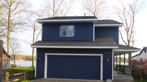 A two-story house with a garage, a covered porch, and a view of a lake.