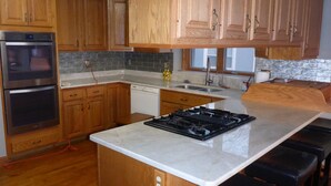 A kitchen with wooden cabinets, a built-in oven, a dishwasher, a stove, and a countertop.