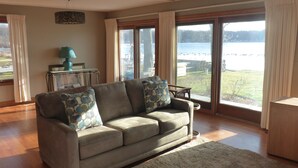 A living room with a sofa, a lamp, and a view of a lake.