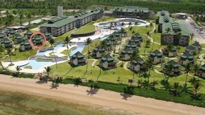 Vista aérea de un complejo turístico con varias edificaciones, un amplio área de piscina y abundante vegetación.