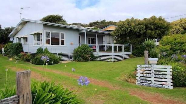 A single-story house with a porch, surrounded by a well-maintained lawn and garden.