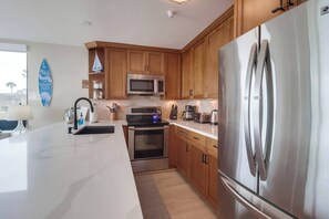 A modern kitchen with wooden cabinets, stainless steel appliances, and a large island with a sink.
