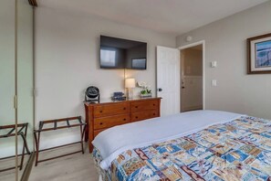 Een slaapkamer met een bed, een kast, een stoel, een spiegel en een deur.