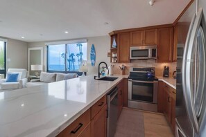Ett modernt kök med en stor köksö, vitvaror i rostfritt stål och träskåp.