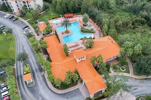 Eine Vogelperspektive eines Hotels mit Schwimmbecken, Palmen und einem Parkplatz.