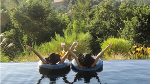 Two people floating in a pool with a scenic view of greenery and hills in the background. - Secluded Vineyard Estate Healdsburg (Healdsburg)