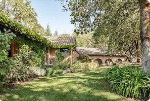 Una casa con tejado de tejas, rodeada de abundante vegetación y un césped cuidado.