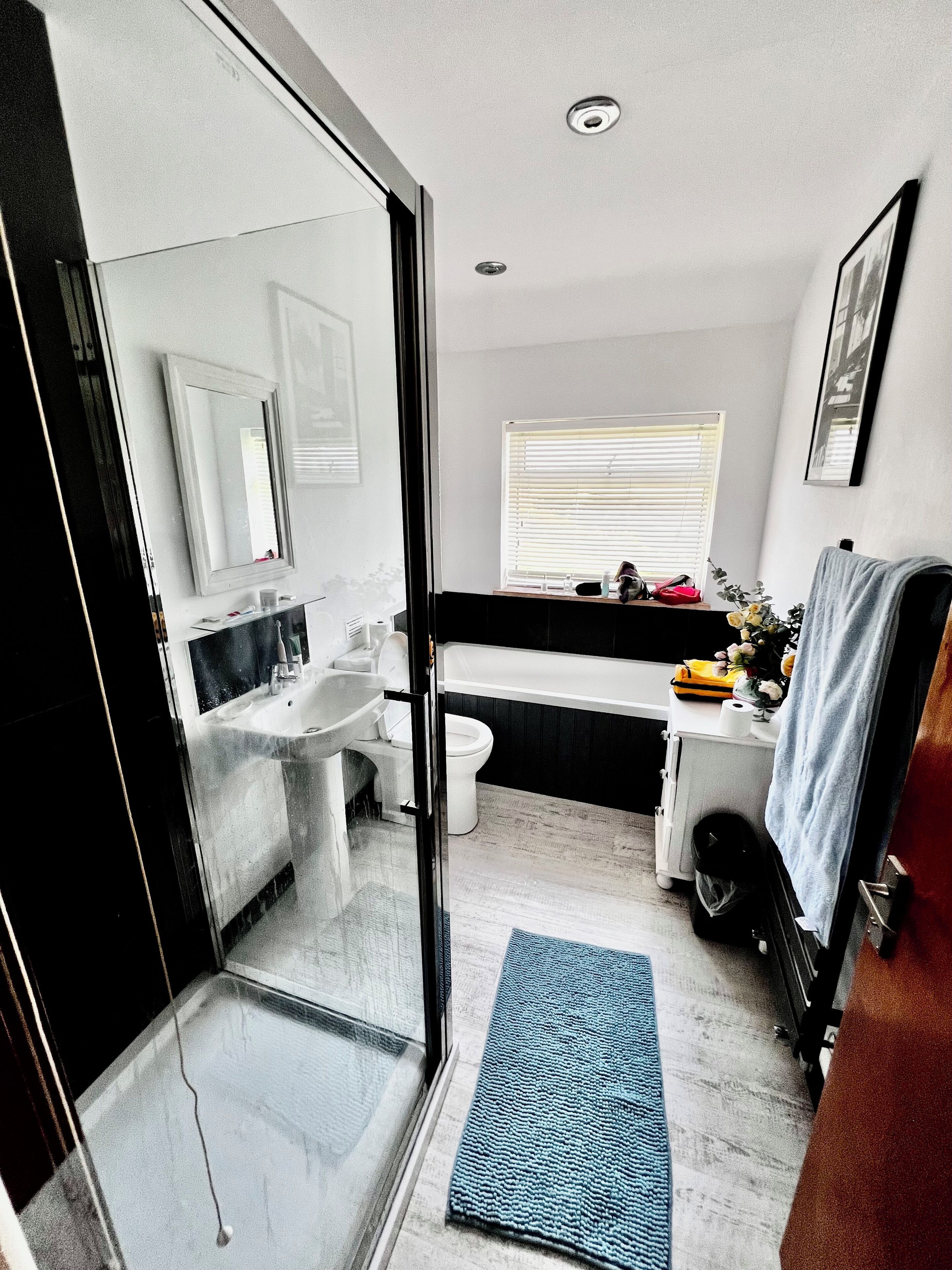 Een moderne badkamer met een douchecabine met glazen deur, een wastafel, toilet en een bad.