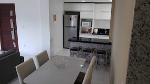 Angolo ristoro con tavolo e sedie, cucina con frigorifero e microonde, e schienale con decorazioni.