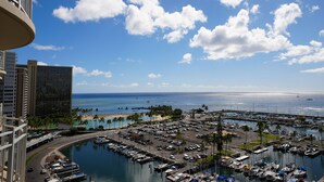 Un port de plaisance avec des bateaux, un espace de stationnement et une plage bordée de palmiers.