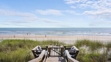 Une promenade en bois qui mène à une plage offrant une vue sur l’océan.