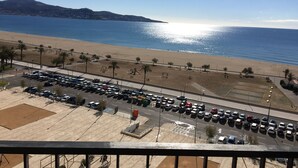 Un parking rempli de voitures, une plage et un ciel dégagé.