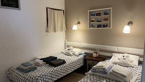 Une chambre d’hôtel avec deux lits, chacun recouvert d’une couvre-lit à motifs, une petite table de chevet et un cadre photo fixé au mur, contenant des photos.