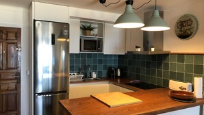 Une cuisine moderne dotée d’un réfrigérateur en acier inoxydable, d’un plan de travail en bois et d’un revêtement mural vert.