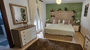 Una camera da letto con un letto, una cassettiera, comodini e una parete verde.