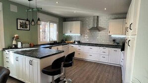 Una cucina moderna con mobili bianchi, un piano di lavoro in marmo e illuminazione a sospensione.
