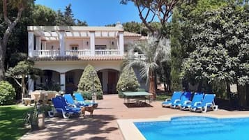 Een buitenzwembad, ligstoelen bij het zwembad