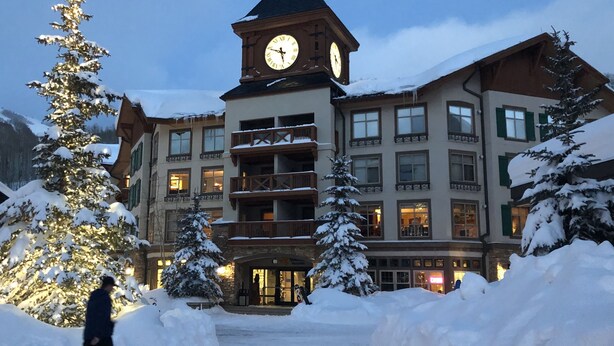A hotel with a prominent clock tower, multiple balconies, and snow-covered surroundings. - Ski in/out Premium Solitude Powderhorn Lodge 1BR (SOLITUDE)