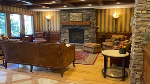 A cozy living room with a fireplace, leather sofa, and plaid armchairs. - Ski in/out Premium Solitude Powderhorn Lodge 1BR (SOLITUDE)