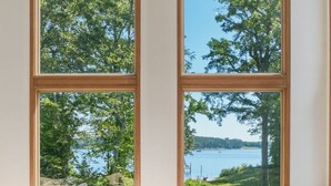 A living room with a large sectional sofa, a wooden coffee table, and two large windows with a view of trees and water. - Waterfront Retreat w/ Pool, Hot Tub, Dock & Sand Beach. Relax & enjoy the Rivah! (Lancaster)