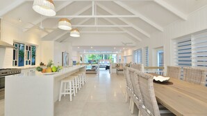 A spacious kitchen with a central island, white cabinetry, and a large dining area with wicker furniture.