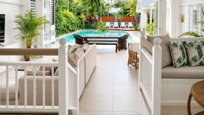 A sunlit room with a pool, white furniture, and tropical plants.