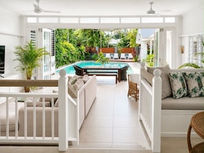 A sunlit room with a pool, white furniture, and tropical plants. - Beach Pavilions - Barefoot luxe with beach house vibes. (Port Douglas)