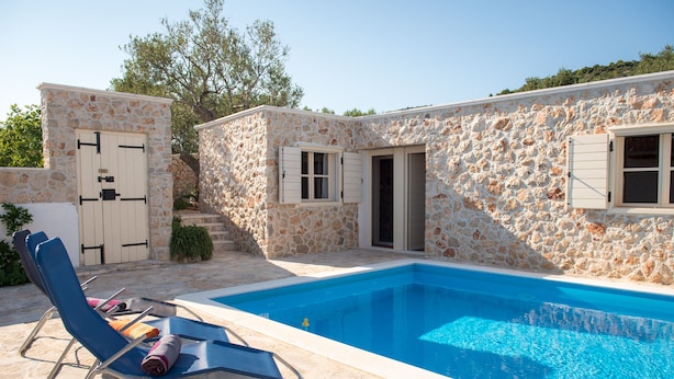 Un edificio in pietra con piscina, una porta e una finestra.