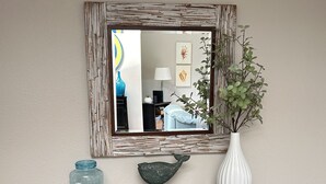 Une console surmontée d’un miroir, agrémentée d’un poisson décoratif, d’un vase et d’une plaque portant l’inscription « Les pieds dans le sable ».