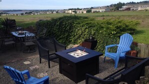 Une terrasse extérieure dotée d’un foyer, de sièges et offrant une vue sur un quartier résidentiel.