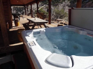 Ein Whirlpool mit Holzterrasse, Sitzgelegenheiten im Freien und Blick auf die umliegende Landschaft.