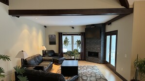 A living room with a fireplace, leather sofas, a coffee table, and potted plants. - Luxury Home w/INDOOR POOL 20mins BarHarbor boardersAcadia National Par (Bernard)