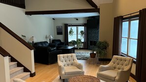 A spacious living area with a high ceiling, a fireplace, and a staircase. - Luxury Home w/INDOOR POOL 20mins BarHarbor boardersAcadia National Par (Bernard)