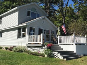 Stunning two-story house with a charming front porch and deck area, featuring a large window and a door with a glass panel.