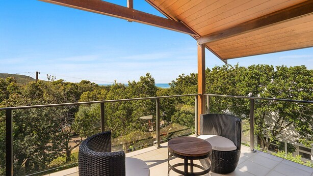 A balcony with wicker furniture and a view of the sea. - Eucalyptus Beach House by HolidayCo. (KILLCARE)