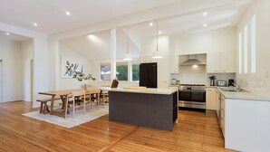 A modern kitchen with a central island, wooden flooring, and pendant lighting. - Eucalyptus Beach House by HolidayCo. (KILLCARE)