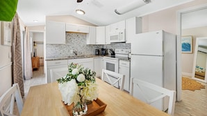 Une cuisine moderne avec des armoires blanches, un comptoir en marbre et un ventilateur de plafond.