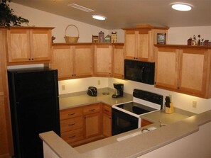 Compact kitchen area with a refrigerator, microwave, stove, and coffee maker.