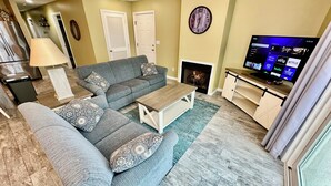 Un salon avec un canapé, une table basse, un téléviseur et une cheminée.