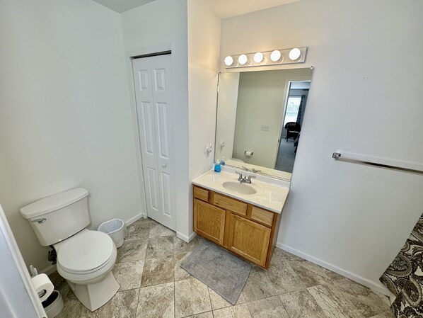 A bathroom with a toilet, sink, and mirror with lights. - Shore Thing, 100 Steps to the Beach, Boardwalk and Sand, BBQ, WiFi (Wildwood)