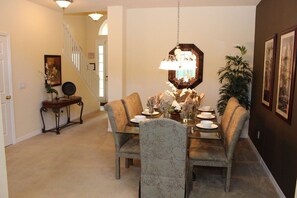 A dining area with a chandelier, chairs, a table set for four, and a staircase in the background. - Huge 6 Bedroom Home in Gated Cypress Pointe Forest - CP001 (Davenport)