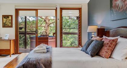 Romanttinen ylellisyysstudio viileässä puiden topassa, jossa on ulkokylpytynnyri ja takka