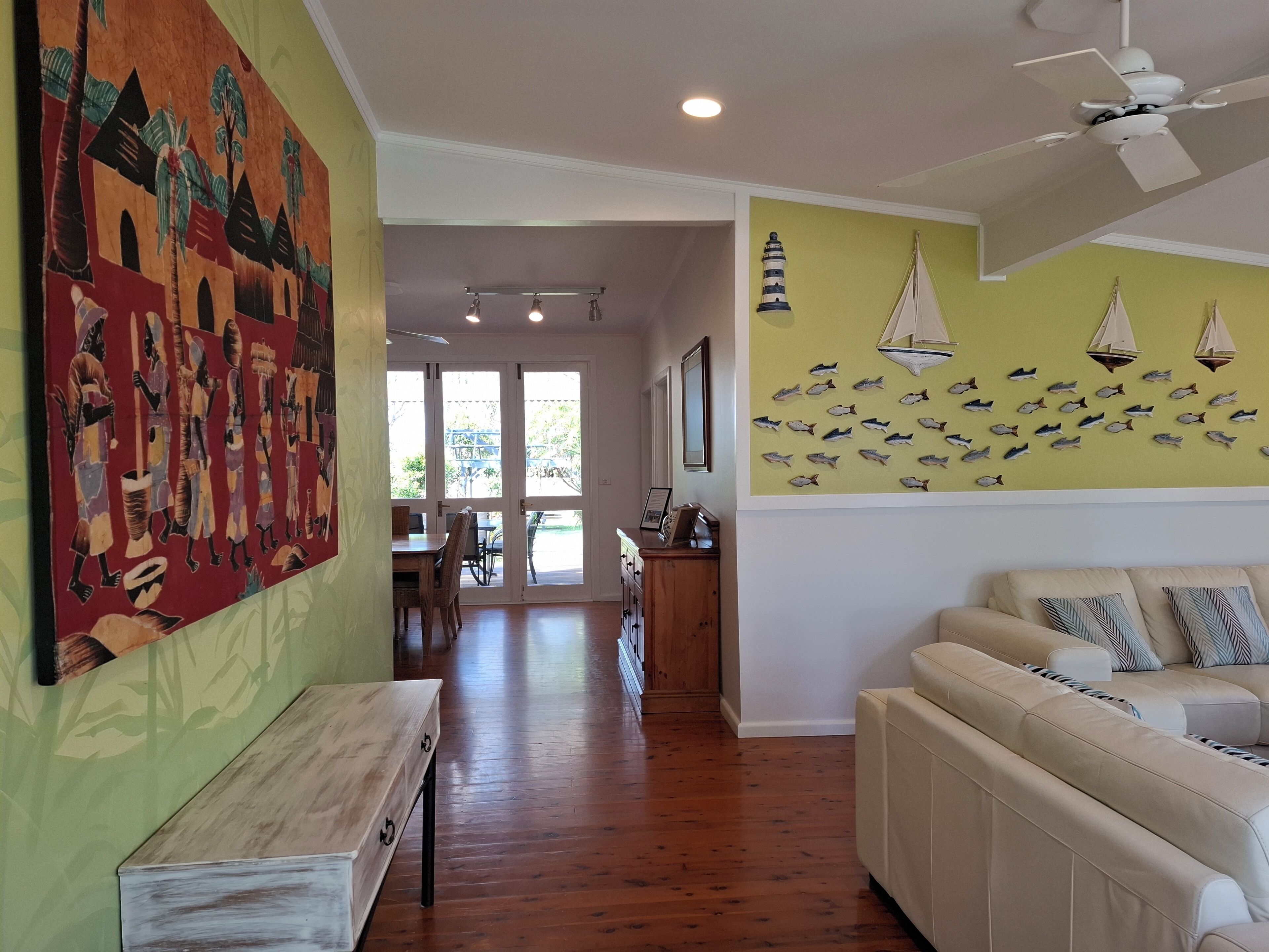 A spacious living room with a wooden floor, a white sofa, and a dining area with a table and chairs.