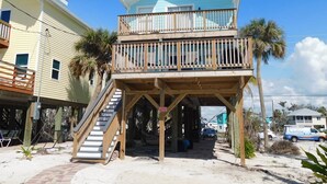 A two-story beach house with a wooden deck and a balcony. - Spectacular Beach Cottage, Pet Friendly, Gulf Views, Great for Families (Fort Myers Beach)